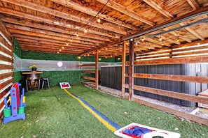 An indoor space with a wooden ceiling, artificial grass flooring, and a green wall.