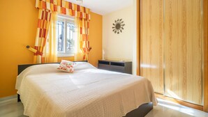 Ein Schlafzimmer mit Bett, Vorhängen, Schreibtisch und Kleiderschrank.