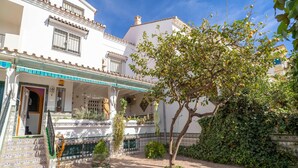 Ein Innenhof mit gefliestem Boden, einem Baum und einem Gebäude mit einem gepflasterten Dach und einem Balkon.