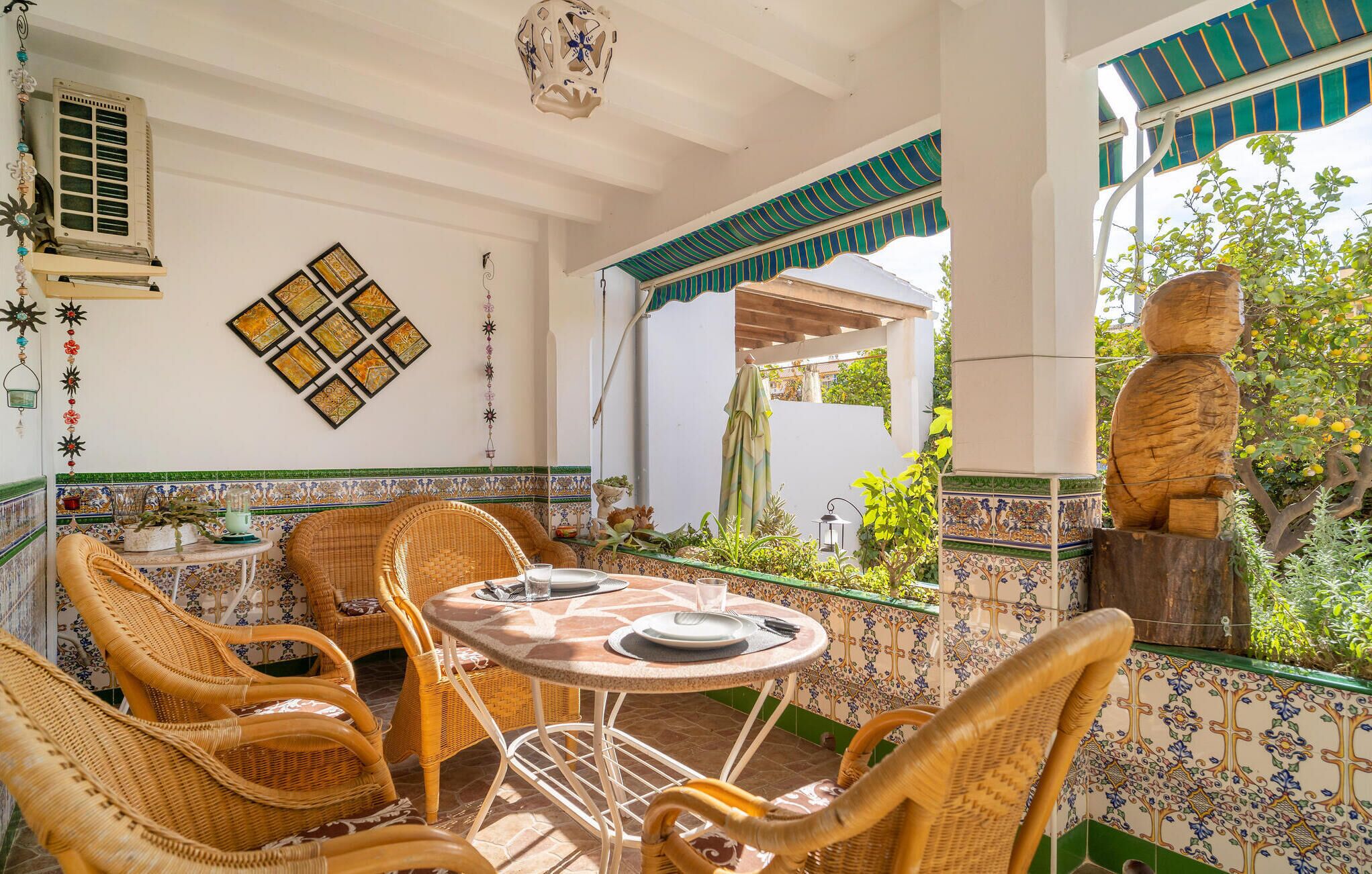 Un patio con mobili in vimini, pavimento piastrellato e parete decorativa.