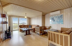Relax in this inviting space with a large window offering views of the outdoors, a comfortable sofa, and a TV on a stand.