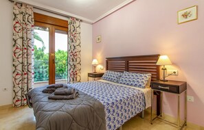 Ein Schlafzimmer mit einem Bett, zwei Nachttischen mit Lampen, einem Fenster mit Vorhängen und einem Bild an der Wand.