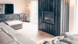 Ein modernes Wohnzimmer mit einer Eckcouch, einem Kamin und einem an der Wand befestigten Fernseher.