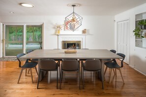 Un comedor con una mesa grande, seis sillas, una chimenea y una lámpara colgante.
