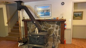 Una estufa de leña con chimenea, una chimenea de piedra y un cuadro en la pared.