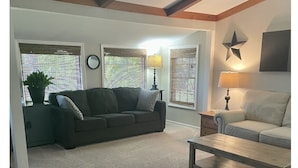 A living room with a sofa, a coffee table, and a lamp. There are windows with blinds and a star decoration on the wall. - Cozy 3 bed, 2 bath home close to historic downtown Hannibal (Hannibal)
