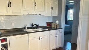 A kitchen with white cabinets, a granite countertop, and a wooden floor. - Cozy 3 bed, 2 bath home close to historic downtown Hannibal (Hannibal)