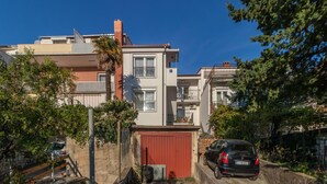 Ein Wohngebäude mit roter Garagentür, einem Balkon und einem geparkten Auto.
