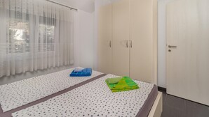 Ein Schlafzimmer mit einem Bett, einem Kleiderschrank und einem Fenster mit Vorhängen.