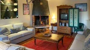 A living room with a fireplace, sofas, a coffee table, and a television.