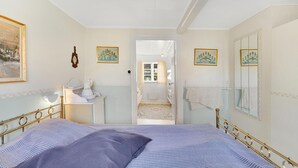 A bedroom with a bed, a bedside table, a mirror, and a window.