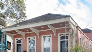 A two-story house with a porch, a front door, and a staircase leading to the entrance.