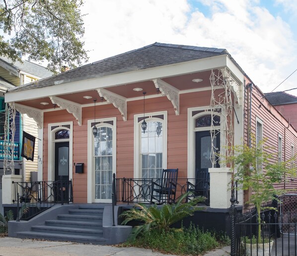 A two-story house with a porch, a set of stairs leading to the front door, and a small garden area. - Beautifully updated New Orleans Home *sleeps 10* (New Orleans)