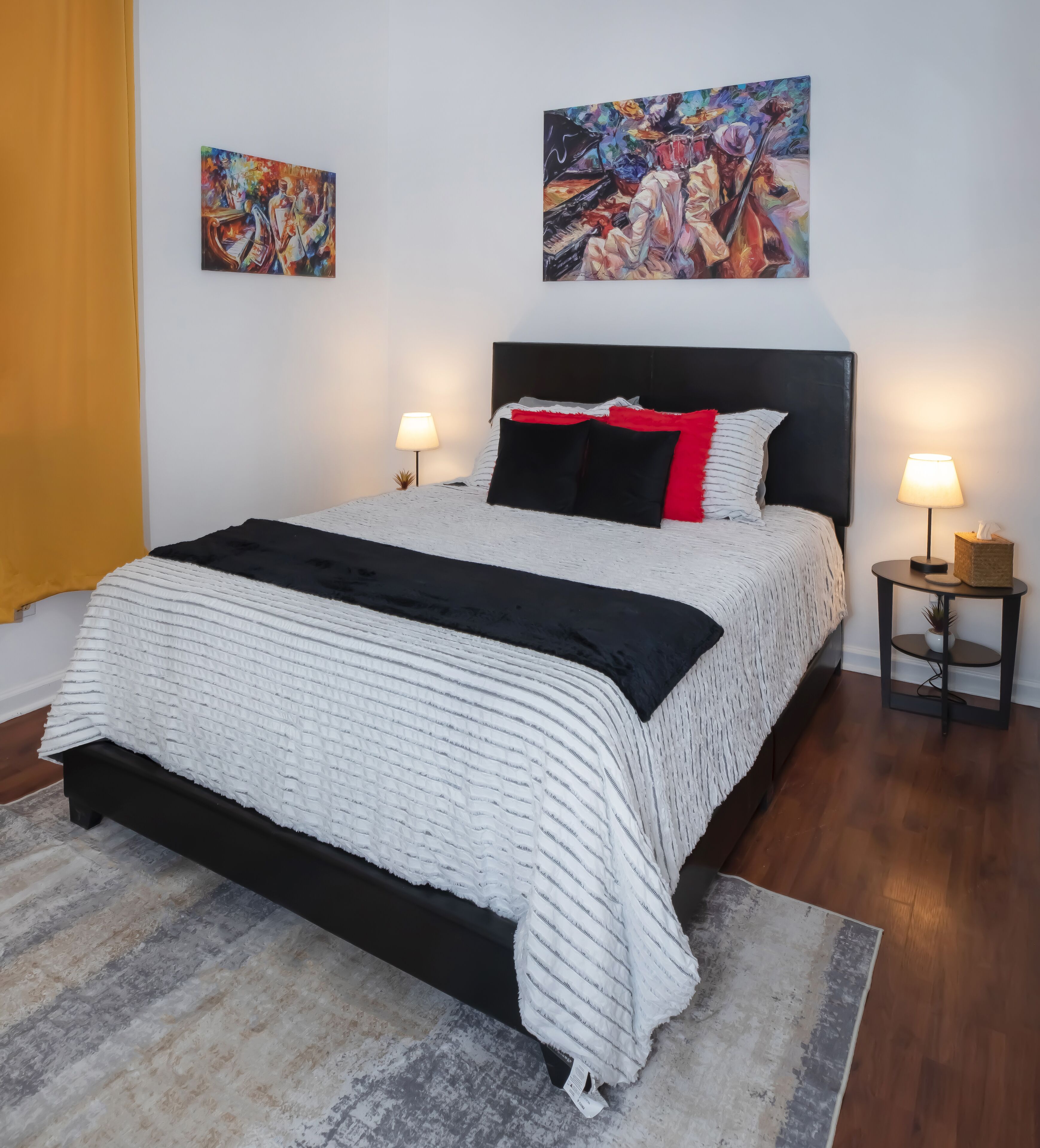 Ein Schlafzimmer mit einem großen Bett, zwei Nachttischen, einem Teppich und zwei Bildern an der Wand.