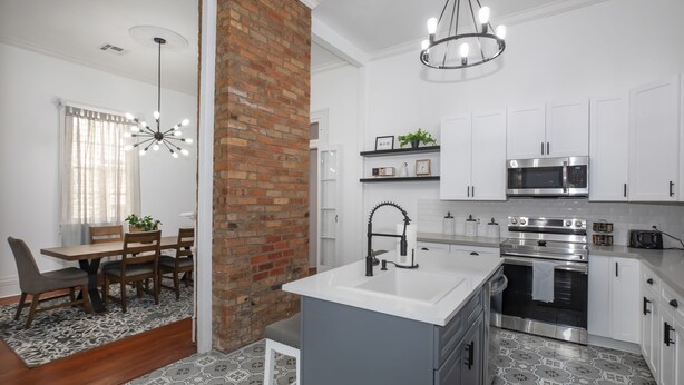 A modern kitchen with white cabinets, a central island with a sink, and stainless steel appliances.