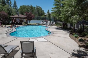 A swimming pool with lounge chairs and a covered area with a flag. - Contemporary Tahoe Lakeside Townhome (Tahoe City)