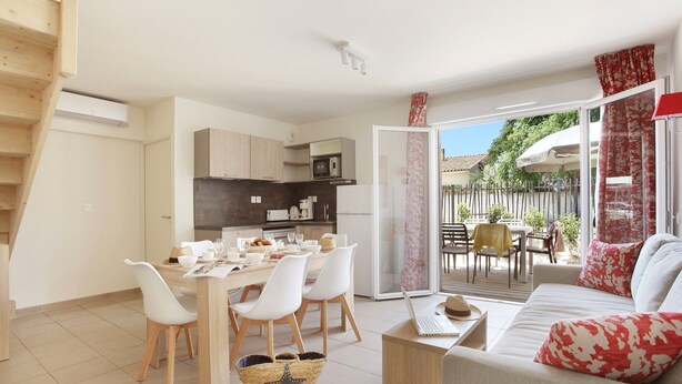 Un appartement moderne comprenant un coin repas, une kitchenette et un salon avec un canapé et un balcon.