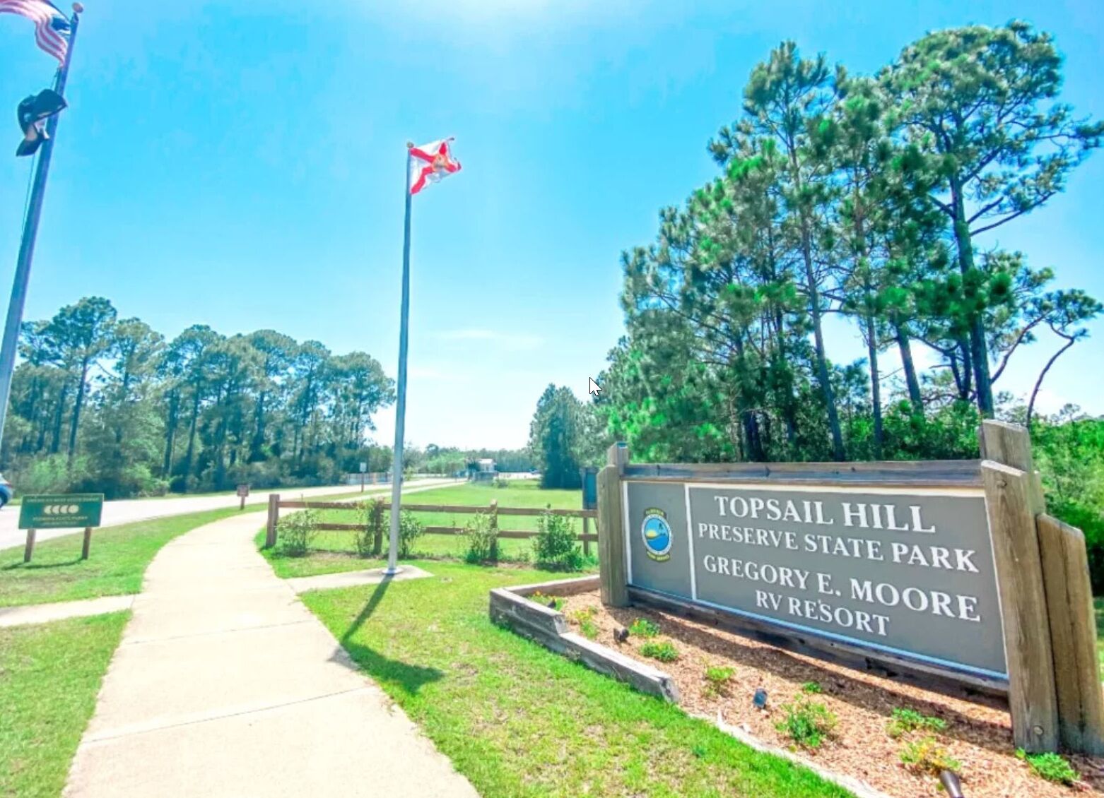 A sign for Topsail Hill Preserve State Park with a clear pathway leading to the entrance.
