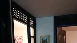 A room with a bed, a wooden floor, a wall with framed pictures, and a partially open door leading to another room. - Nice Chia Apartment (Chía)