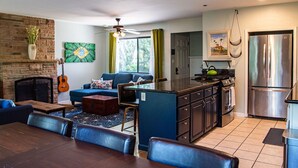 A modern kitchen with a built-in stove, stainless steel refrigerator, and a dining area with a wooden table and chairs. - Family Home Near Bidwell Park (Chico)