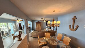 A spacious living room with a large sofa, wicker chairs, a glass-top dining table, and a ceiling fan. - Tranquil Waterfront Pool Home with beautiful views and sunsets and great fishing (Port Charlotte)