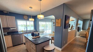 A modern kitchen with a central island, built-in appliances, and large windows offering views of the outdoors. - Tranquil Waterfront Pool Home with beautiful views and sunsets and great fishing (Port Charlotte)