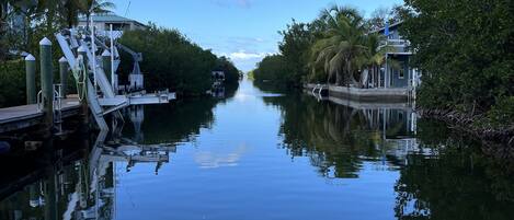 A calm waterway flanked by lush greenery and a modern building.