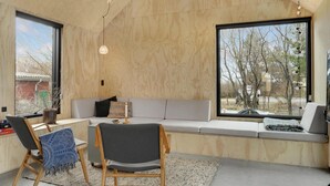 Et moderne interiør med en trævæg, en sofa, en bænk og udsigt til træer.