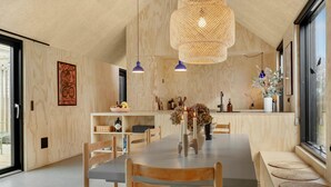 Et moderne spiseområde med et træbord, stole og en stor vævet lampe.
