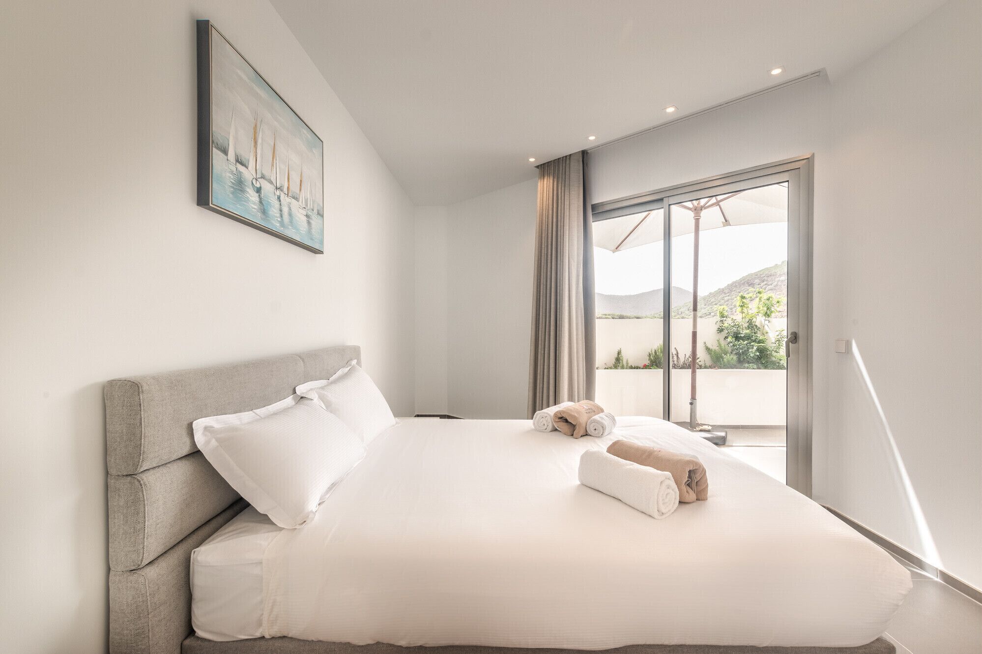 Une chambre d’hôtel moderne avec un grand lit, un tableau au mur et une vue sur l’extérieur.