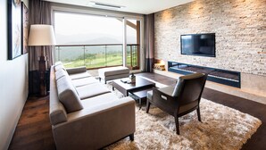 A modern living room with a large window, a flat-screen TV mounted on a brick wall, and a cozy seating area. - Sono Felice Village Vivaldi Park (Hongcheon)