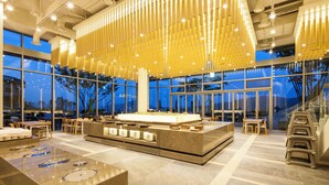 A spacious lobby with a central island, seating areas, and large windows offering views of the outdoors. - Sono Felice Village Vivaldi Park (Hongcheon)