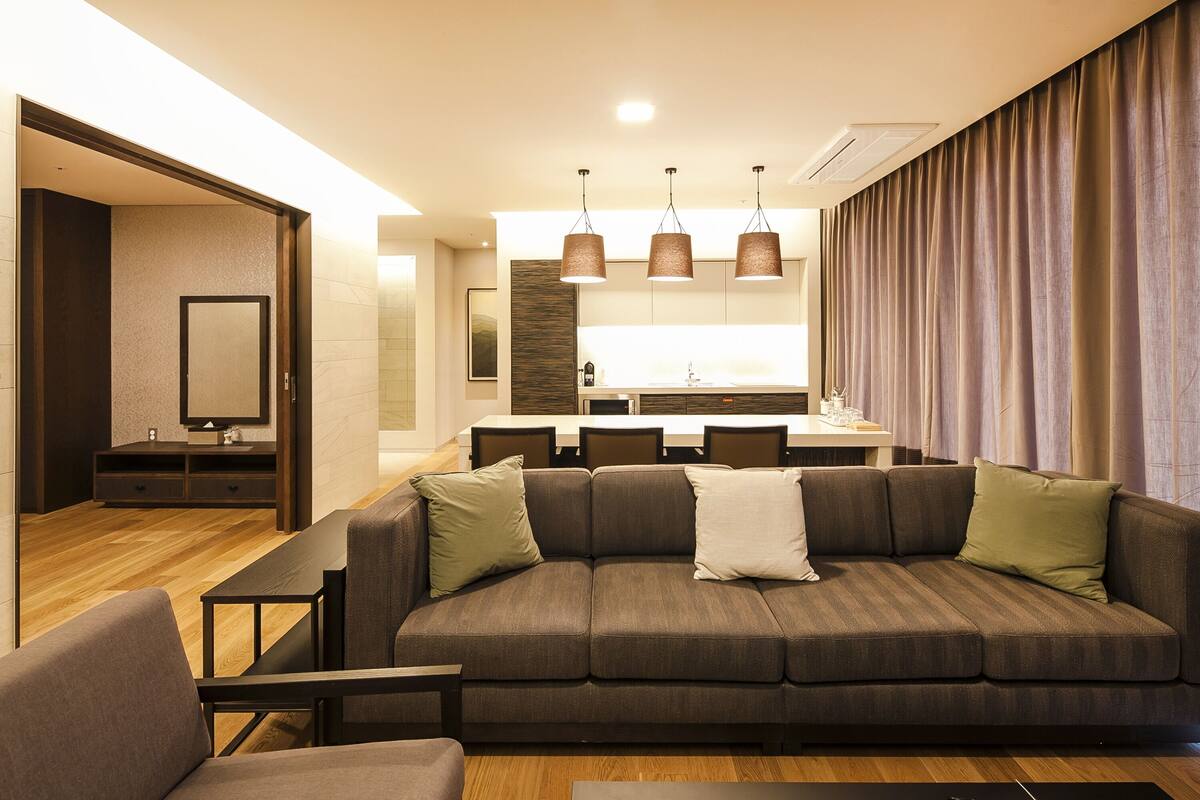 A modern living room with a sofa, a TV, and a dining area with a table and chairs.