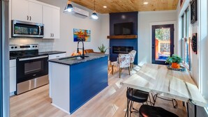 Una cocina moderna con armarios blancos, una isla central, electrodomésticos de acero inoxidable y techo de madera.