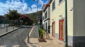 Eine Kopfsteinpflasterstraße mit Gebäuden an einer Seite und einer Hügelkulisse im Hintergrund.