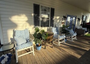 En træterrasse med udendørs møbler, herunder stole og et bord, samt en potteplante.