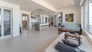 A spacious living area with a sofa, a coffee table, and a view of the kitchen and dining area. - Gosung Stager (Goseong)