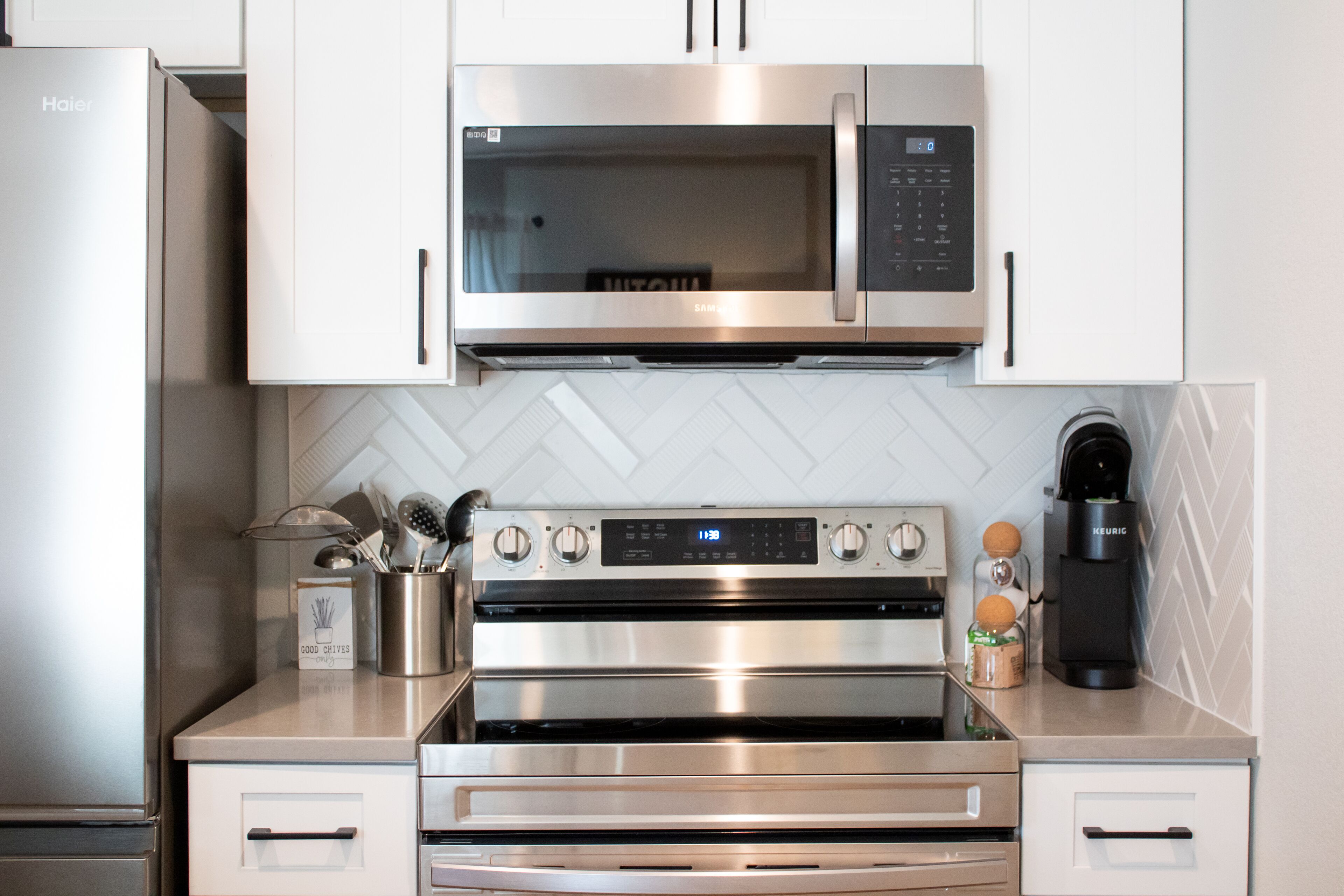 A modern kitchen with stainless steel appliances including a microwave, oven, and coffee maker.