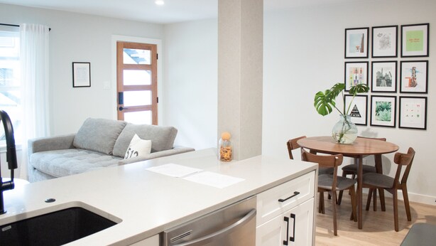 A modern kitchen with a white countertop, a sink, and wooden cabinets. There is a dining area with a round table and chairs. - Newly Renovated Modern Condo- Walk to Zilker & Barton Springs! Private backyard! (Austin)