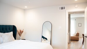 A bedroom with a bed, a large mirror, and a view into another room with a sofa. - Newly Renovated Modern Condo- Walk to Zilker & Barton Springs! Private backyard! (Austin)