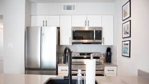 A modern kitchen with stainless steel appliances, white cabinetry, and a marble countertop. - Newly Renovated Modern Condo- Walk to Zilker & Barton Springs! Private backyard! (Austin)