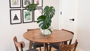 A dining area with a round wooden table, four chairs, and a large green plant in a vase. - Newly Renovated Modern Condo- Walk to Zilker & Barton Springs! Private backyard! (Austin)