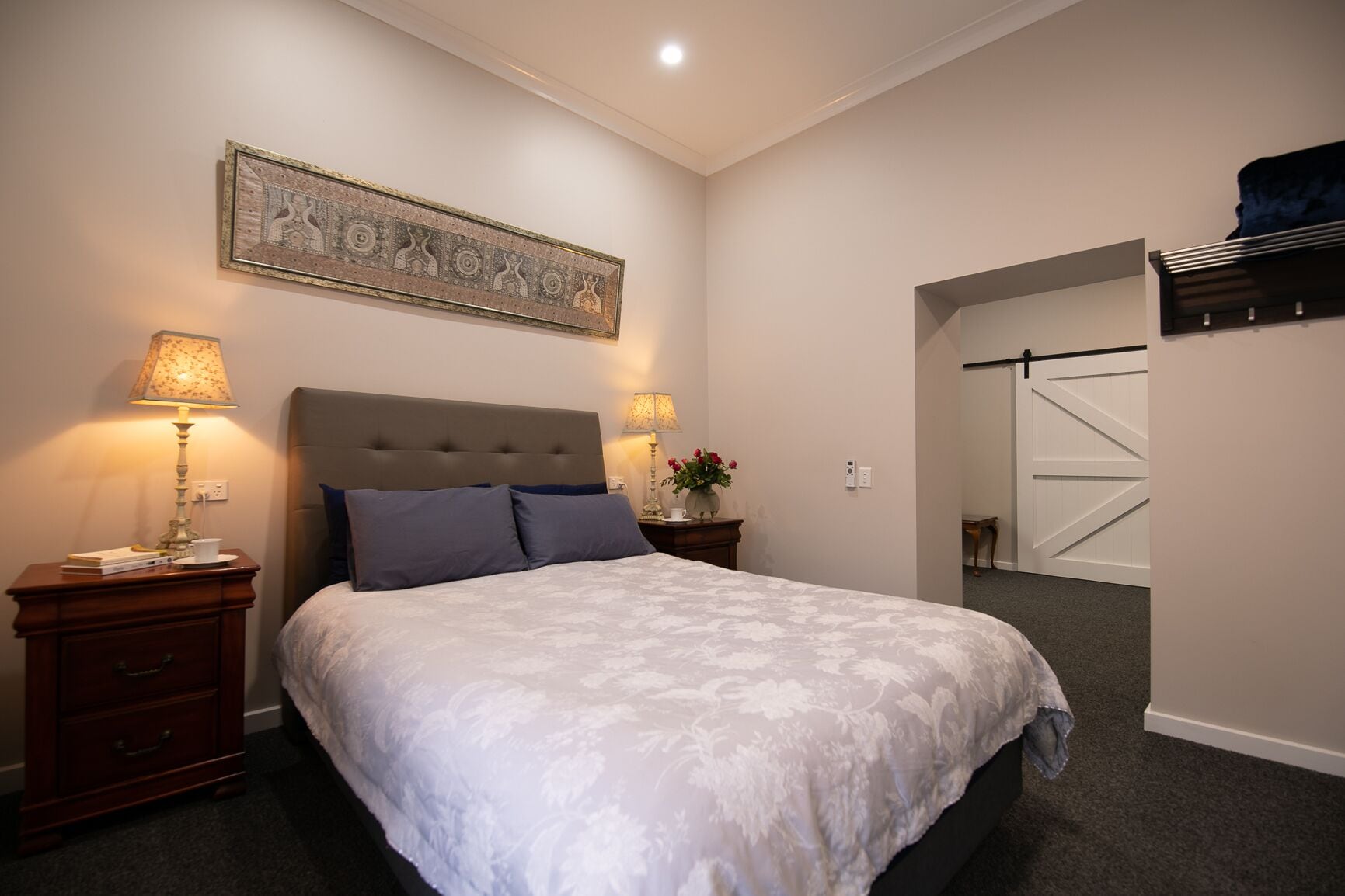 A bedroom with a large bed, two bedside tables with lamps, a wall-mounted artwork, and a sliding door closet.
