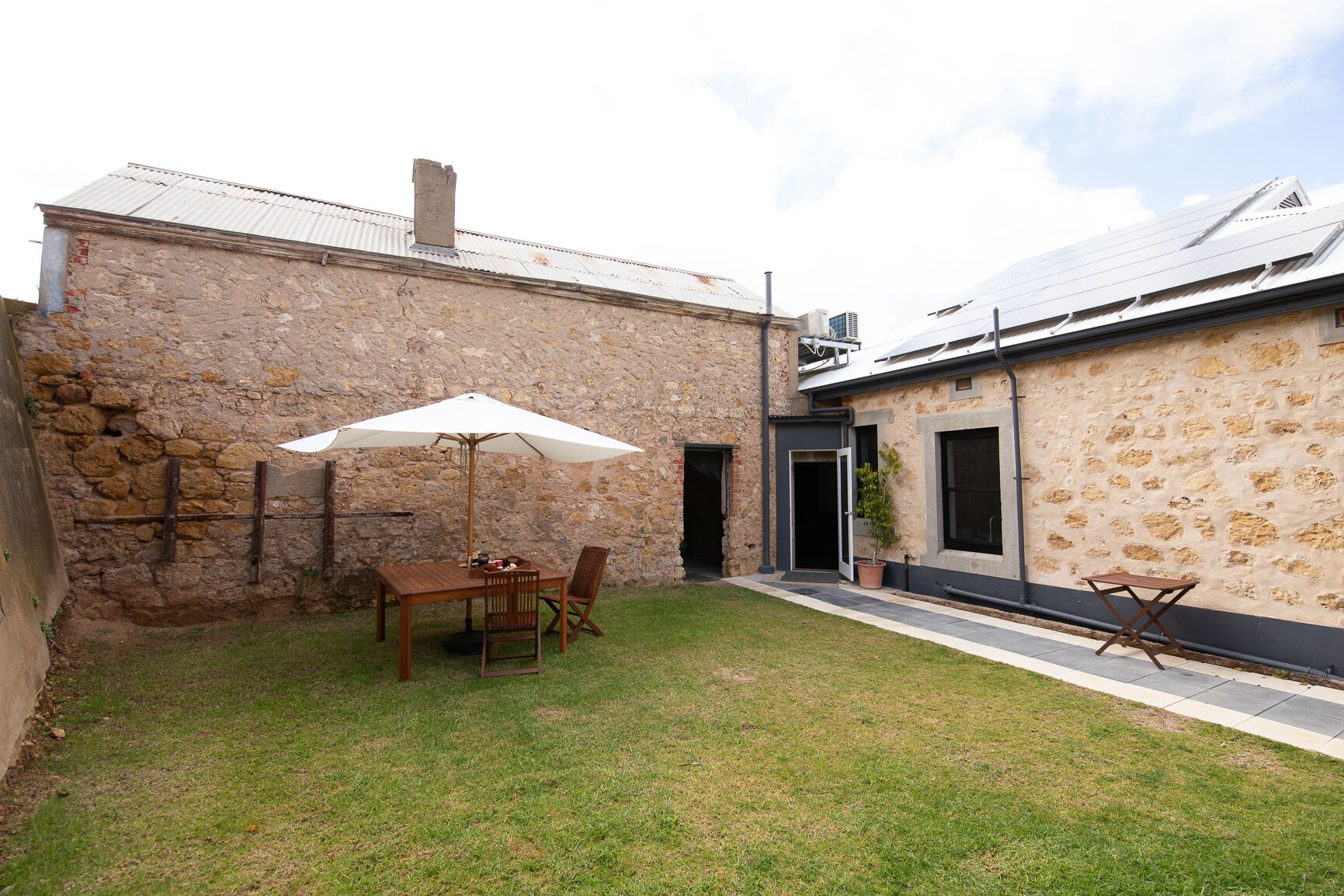A stone building with a patio area featuring a table and chairs under a white umbrella.