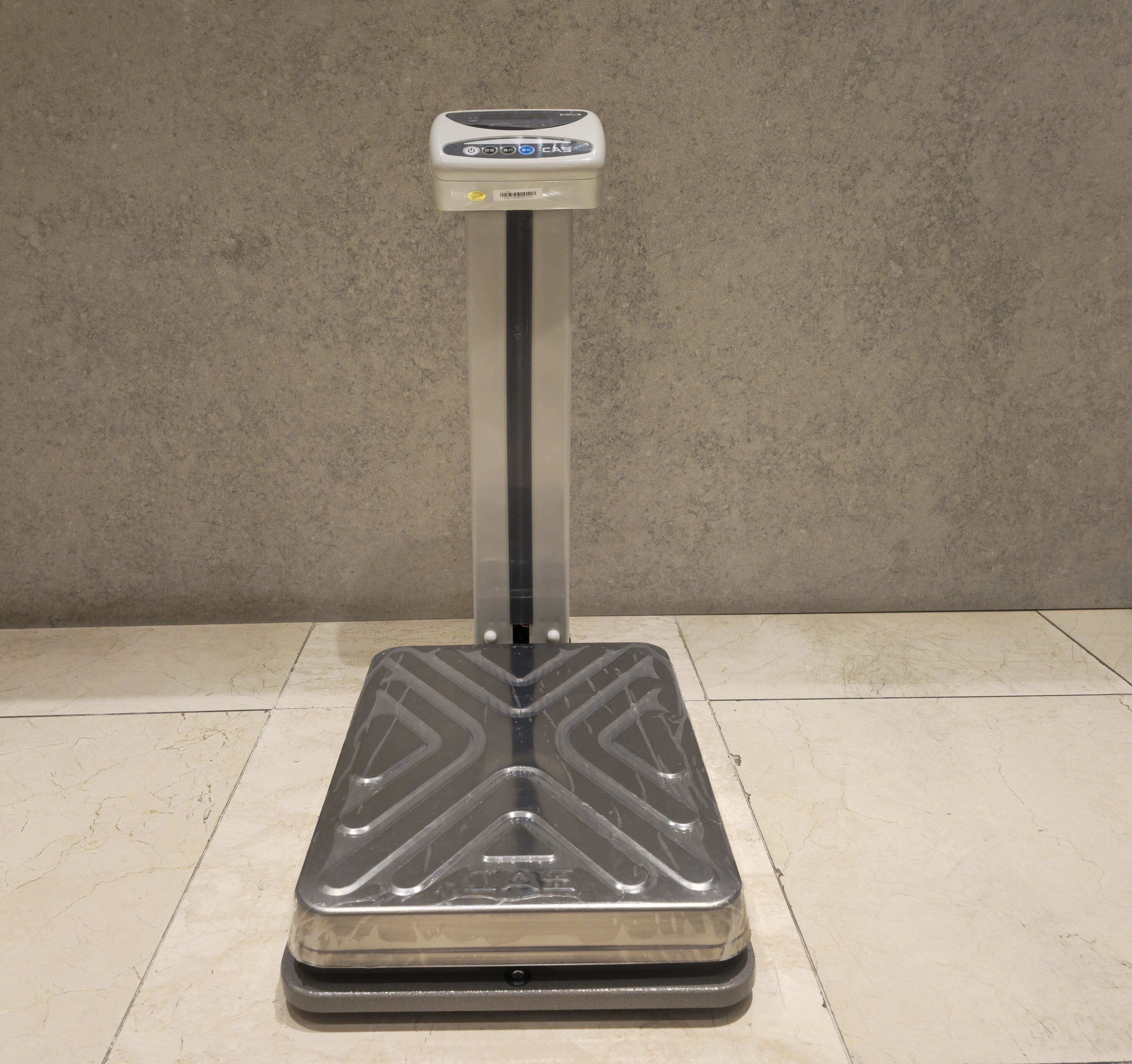 A stationary exercise machine with a digital display and control panel, placed on a tiled floor.
