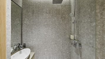 A modern bathroom with a marble shower, a sink with a mirror, and a glass partition.