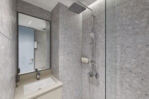 A modern bathroom with a rectangular sink, a large mirror, and a shower with a handheld showerhead.