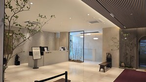 Un área de recepción moderna de hotel, con un mostrador de recepción, un banco y un separador de vidrio.