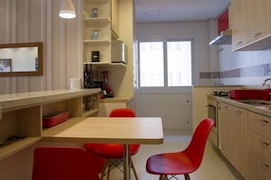 Een moderne keuken met een eetgedeelte, met een houten tafel, rode stoelen en een raam met uitzicht.