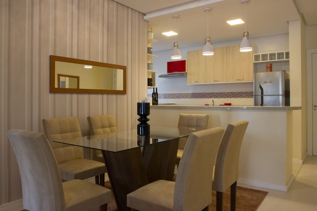Una cocina moderna con una isla central, iluminación colgante y una zona de comedor con mesa y sillas de vidrio.